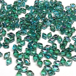 May include: A scattering of teal green iridescent glass beads, each with a faceted diamond shape.