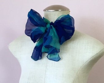 May include: A blue and green patterned silk bow tie on a white mannequin.