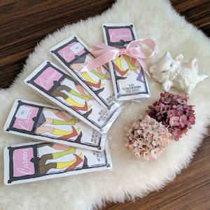 May include: Five colorful cards with the word "Carmen" printed on them. Each card features a different illustration of a woman wearing colorful socks. The cards are arranged in a fan shape on a white fluffy surface.