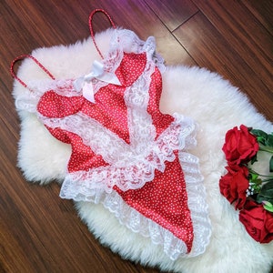 May include: Red satin lingerie with white lace trim and polka dots. The lingerie is on a white fur background with red roses.