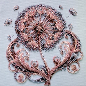 May include: A detailed, beaded artwork depicting a dandelion. The piece features a central seed head in shades of pink, brown, and gray, with delicate stems and stylized leaves. The background is a light, textured fabric.