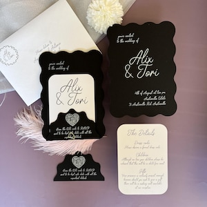 May include: Black and white wedding invitation with a scalloped edge. The invitation features the couple's names, "Alix & Tori", and the date and time of the wedding. The invitation also includes a QR code for guests to RSVP.