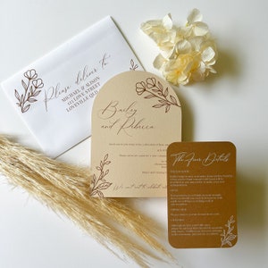 May include: A wedding invitation suite with a brown and cream color scheme. The invitation features a floral arch design with the names "Bailey and Rebecca" in cursive script. The RSVP card includes the text "The Finer Details" and details about the wedding venue, dress code, and children.