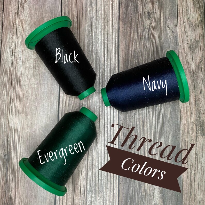 May include: Three spools of thread in black, navy blue, and evergreen green. The spools are labelled with their respective colours. The text "Thread Colours" is written in a brown banner.