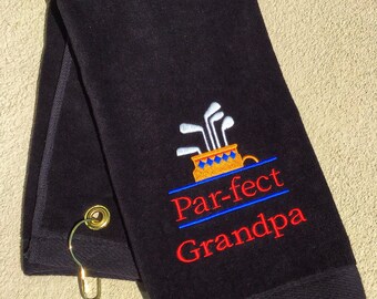May include: Black golf towel with a gold golf cart and clubs embroidered on it. The text "Par-fect Grandpa" is embroidered in red and blue.