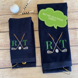 May include: Two navy blue golf towels with white golf club and ball embroidery. The towels have the letters "R" and "T" embroidered in green. The larger towel has the text "Adult Towel Can Be Purchased Separately" in a green speech bubble.
