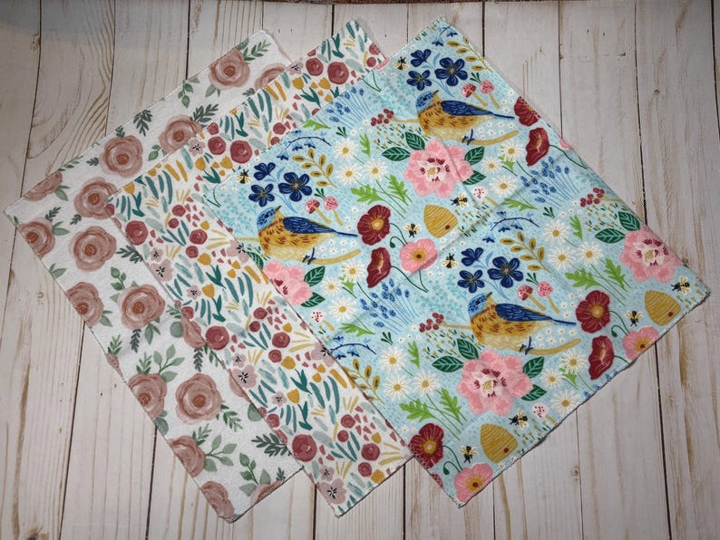 Puede incluir: Cuatro pa&ntilde;os con estampados florales. Un pa&ntilde;o presenta un patr&oacute;n de rosas en tonos marrones y blancos. Otro pa&ntilde;o tiene un estampado floral con acentos rojos, rosas y verdes. Los otros dos pa&ntilde;os tienen un fondo azul con p&aacute;jaros, flores y abejas.