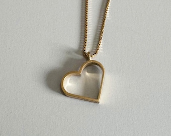 May include: A gold chain necklace with a hollow heart pendant.