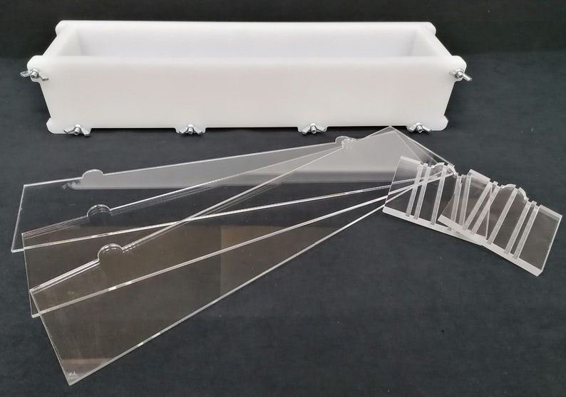 Puede incluir: Un molde de jab&oacute;n de pl&aacute;stico blanco con forma rectangular y clips met&aacute;licos. El molde viene acompa&ntilde;ado de varios divisores de acr&iacute;lico transparente para crear barras de jab&oacute;n con diferentes dise&ntilde;os.