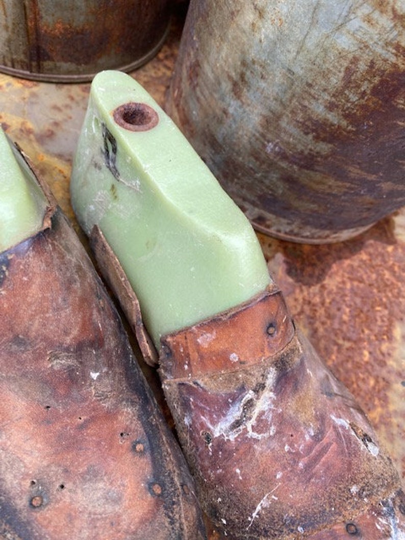 May include: Two brown leather shoe forms with a green plastic insert. The forms are worn and have a distressed look.
