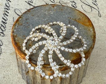 Vintage rhinestone brooch featuring a floral or pinwheel design
