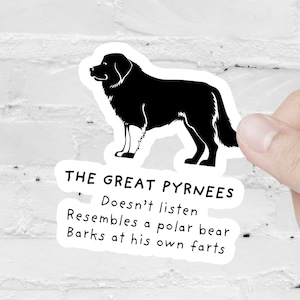 May include: A black and white sticker featuring a Great Pyrenees dog illustration. The sticker includes text that reads "THE GREAT PYRNEES" and humorous descriptions. The sticker is held against a white brick wall.