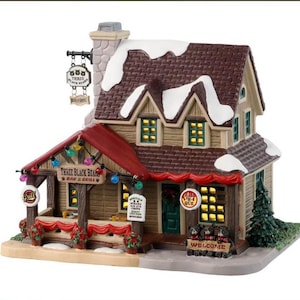 Può includere: Un modello in miniatura di un bar e grill chiamato "Three Black Bears Bar & Grill" con un tetto rosso, un tetto innevato e un portico con decorazioni rosse e bianche. Il cartello sopra la porta dice "Benvenuti".