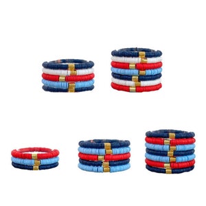 May include: A set of five colorful beaded bracelets in red, white, blue, and gold. The bracelets are stacked on top of each other, creating a layered effect.