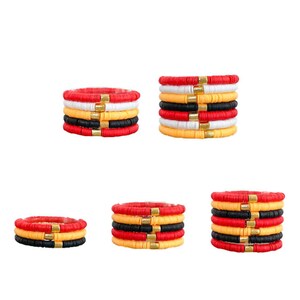 May include: A set of six colorful bracelets with black, white, red, and yellow beads. Each bracelet has a gold accent bead.