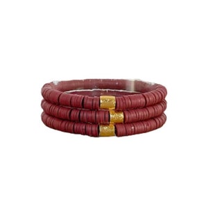 May include: Three stacked bracelets made of maroon colored beads with gold accents.
