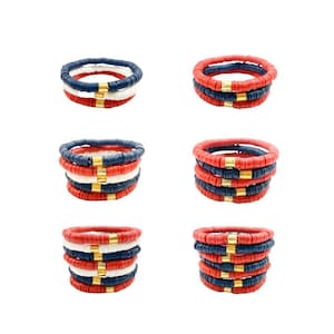 May include: Set of three bracelets with red, white, and blue beads. The beads are stacked on top of each other, creating a layered look. The bracelets are accented with gold beads.