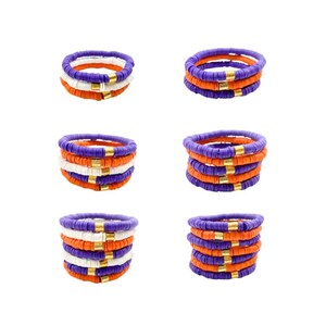 May include: Set of six colorful bracelets made of stacked beads in orange, white, and purple with gold accents.