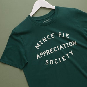 May include: A dark green t-shirt with the text "MINCE PIE APPRECIATION SOCIETY" printed in white on the front.