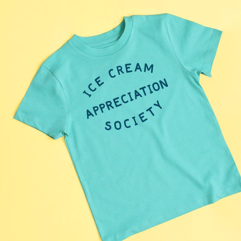 May include: A turquoise blue t-shirt with the text "ICE CREAM APPRECIATION SOCIETY" printed in a circle on the front.