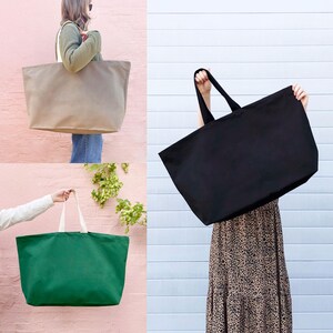 Op de afbeelding: Drie grote canvas tassen in verschillende kleuren: beige, zwart en groen. De tassen hebben brede, platte handvatten en zijn gemaakt van een stevige, natuurlijke stof.
