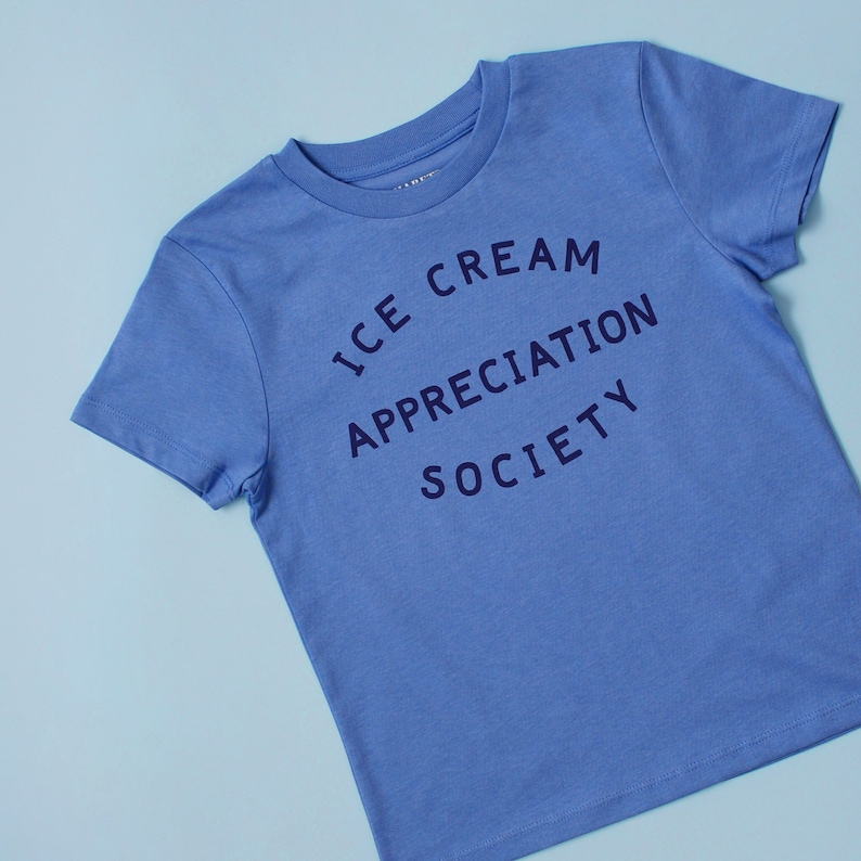 May include: A light blue t-shirt with the text "ICE CREAM APPRECIATION SOCIETY" printed in dark blue.
