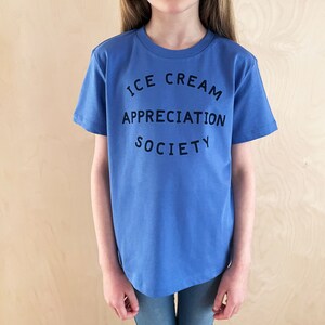 May include: A blue t-shirt with the text "ICE CREAM APPRECIATION SOCIETY" printed on the front.