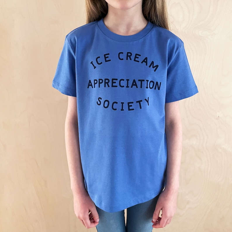 May include: A blue t-shirt with the text "ICE CREAM APPRECIATION SOCIETY" printed on the front.