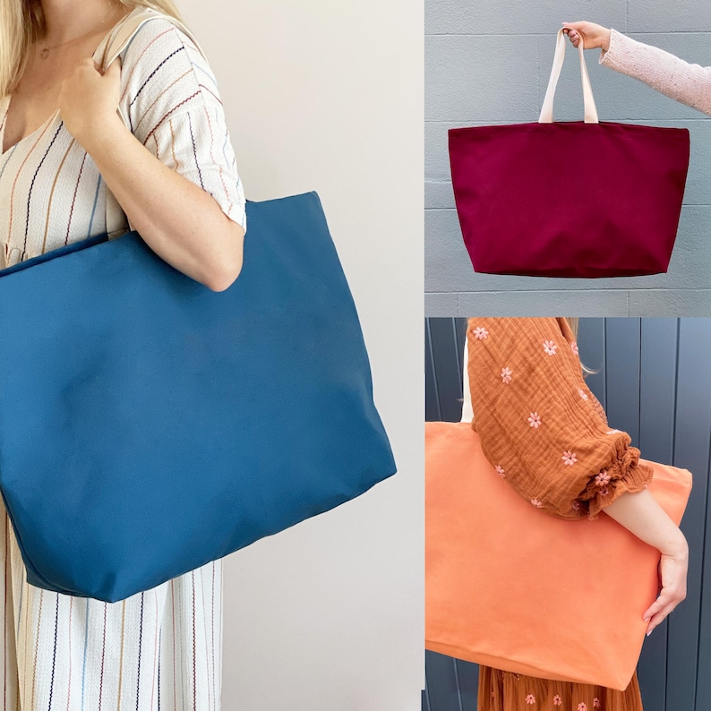 Op de afbeelding: Drie tote bags in verschillende kleuren: teal, bordeauxrood en perzik. De tassen zijn gemaakt van een canvasachtig materiaal en hebben een eenvoudige, rechthoekige vorm.