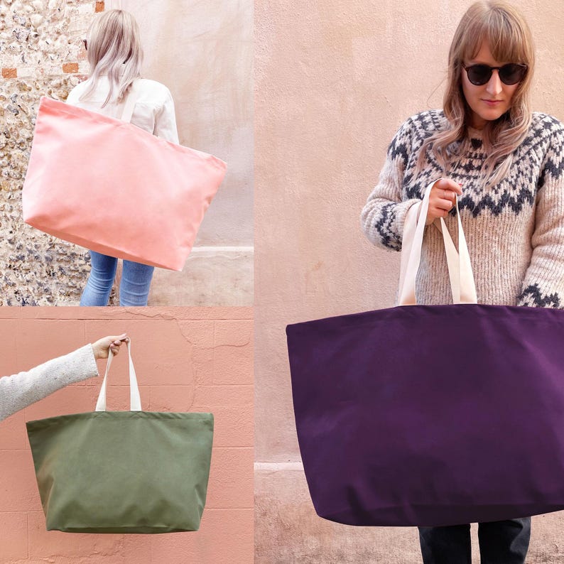 Op de afbeelding: Drie grote canvas tassen in verschillende kleuren: roze, paars en groen. De tassen hebben witte handvatten en zijn gemaakt van stevig canvas materiaal.