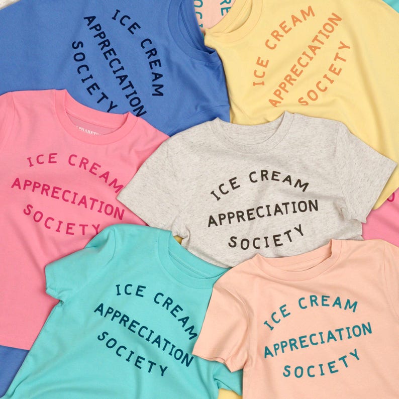 May include: A collection of six t-shirts in various colours, each featuring the text "ICE CREAM APPRECIATION SOCIETY" in a circular design. The shirts are made of cotton and have a casual, relaxed fit.