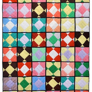 May include: A colorful quilt with a repeating diamond pattern. The quilt features squares of various colors, including red, green, yellow, pink, and blue, separated by black borders. The diamonds are white and the quilt is quilted.
