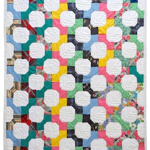 May include: A white quilt with a geometric pattern made from colorful fabric scraps. The quilt is made up of octagons and squares, and the fabric scraps are arranged in a diagonal pattern. The colors of the fabric scraps include pink, yellow, blue, green, and red.