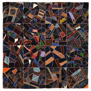 May include: A square, patchwork quilt with a geometric design. The quilt is composed of numerous irregularly shaped fabric pieces in various colors, including black, brown, orange, blue, and purple. The pieces are sewn together with visible stitching, creating a textured surface.