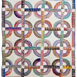 May include: A handmade quilt with a white background and a repeating pattern of colorful half-circles and intersecting lines. The quilt features a variety of fabrics in shades of blue, purple, orange, and yellow, creating a vibrant and eye-catching design. The quilt is bordered with a black trim.