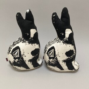 May include: Two black and white patterned fabric bunny rabbit plushes. The bunnies are sitting upright with their ears perked up.
