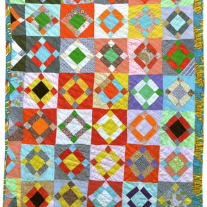 May include: A colorful patchwork quilt with a repeating diamond pattern. The quilt features squares of various colors including red, orange, blue, green, and yellow. The edges are trimmed with a patterned border. The quilt is approximately 70 inches by 80 inches.