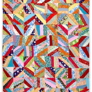 May include: A colorful patchwork quilt with a variety of fabrics in red, white, blue, yellow, and green. The quilt features a diagonal stripe pattern with stars and floral designs. The edges are finished with a white border.