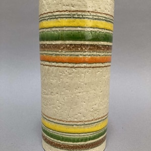May include: A white ceramic vase with a textured surface and multi-colored stripes in shades of green, yellow, orange, and brown.