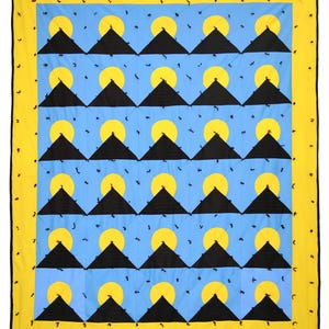 May include: A quilt with a repeating pattern of black triangles, yellow circles, and blue squares. The quilt has a yellow border.