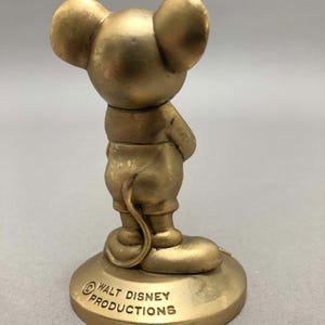 Op de afbeelding: Een gouden beeldje van Mickey Mouse dat op een voet staat met de tekst "&copy; WALT DISNEY PRODUCTIONS".