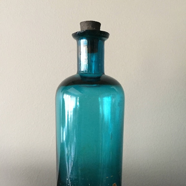 Antique glass bottle, early medicine bottle with bit of label still adhered.  Extraordinary clear teal color with interesting cork.
