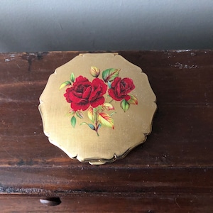 Vintage compact, Stratton, unused with screen.  Beautiful rose image on gold colored textured metal.  Pouch and original box.