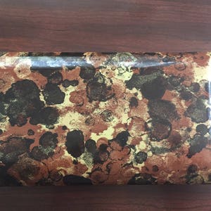 May include: A rectangular tray with a brown, black, and gold camouflage pattern.