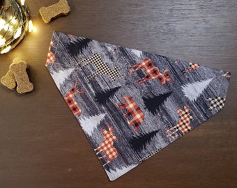 Puede incluir: Un bandana triangular para perro con un patrón de bosque en blanco y negro. El bandana presenta siluetas de alces, osos y árboles en cuadros rojos y negros.