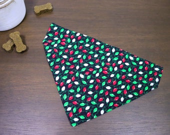Puede incluir: Un bandana negro para perro con un patrón festivo de luces navideñas rojas, verdes y blancas.