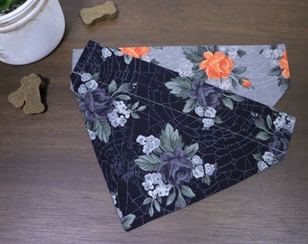 May include: Two dog bandanas, one with a black background and a floral pattern with spiderwebs, and the other with a grey background and a floral pattern with orange flowers.