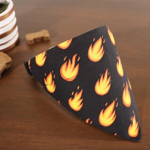 May include: A black bandana with a repeating pattern of orange flames. The bandana is folded into a triangle shape.