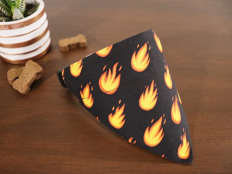 May include: A black bandana with a repeating pattern of orange flames. The bandana is folded into a triangle shape.