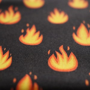 May include: Black fabric with a repeating pattern of orange flames.